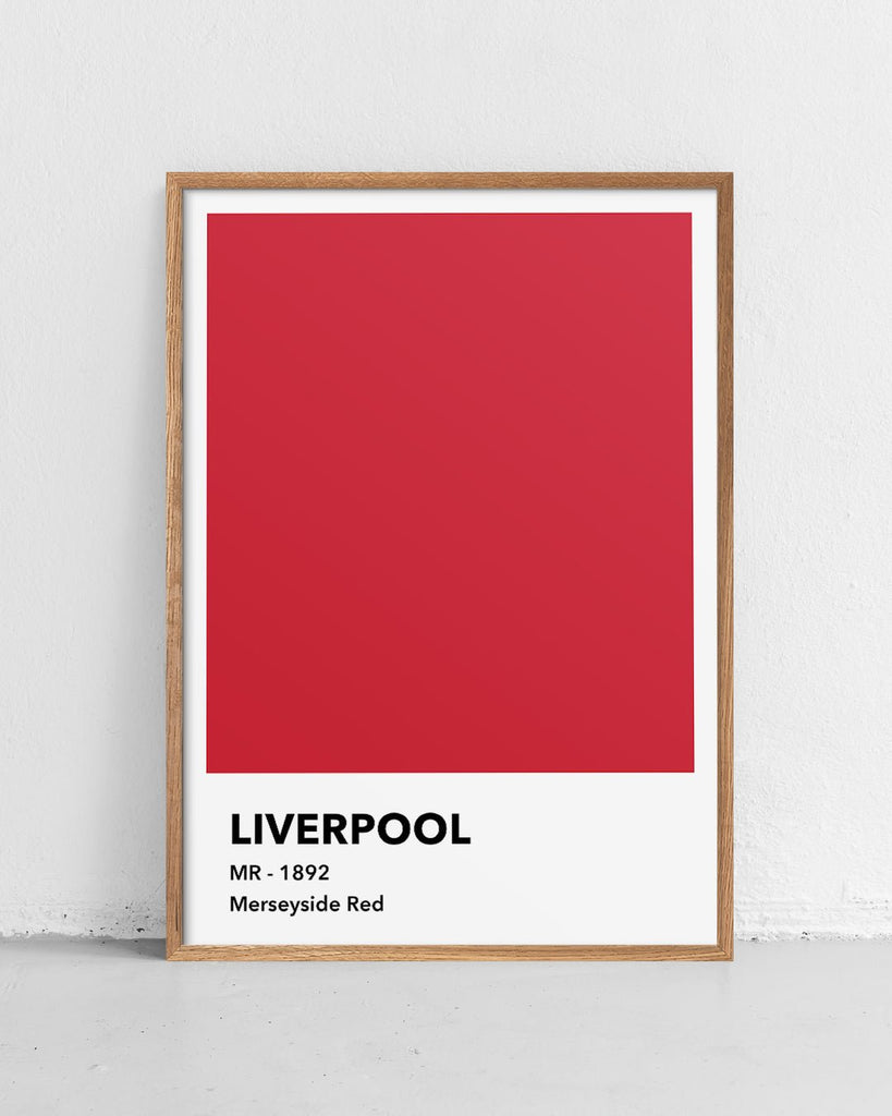 En Liverpool F.C. fodbold plakat med deres røde farve fra Colors kollektionen stående på et gulv - Olé Olé
