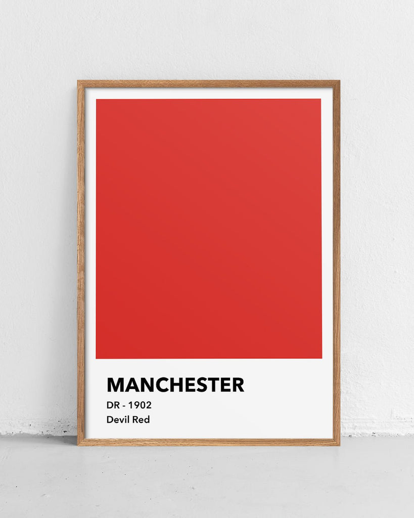 En Manchester United fodbold plakat med deres røde farve fra Colors kollektionen stående på et gulv - Olé Olé