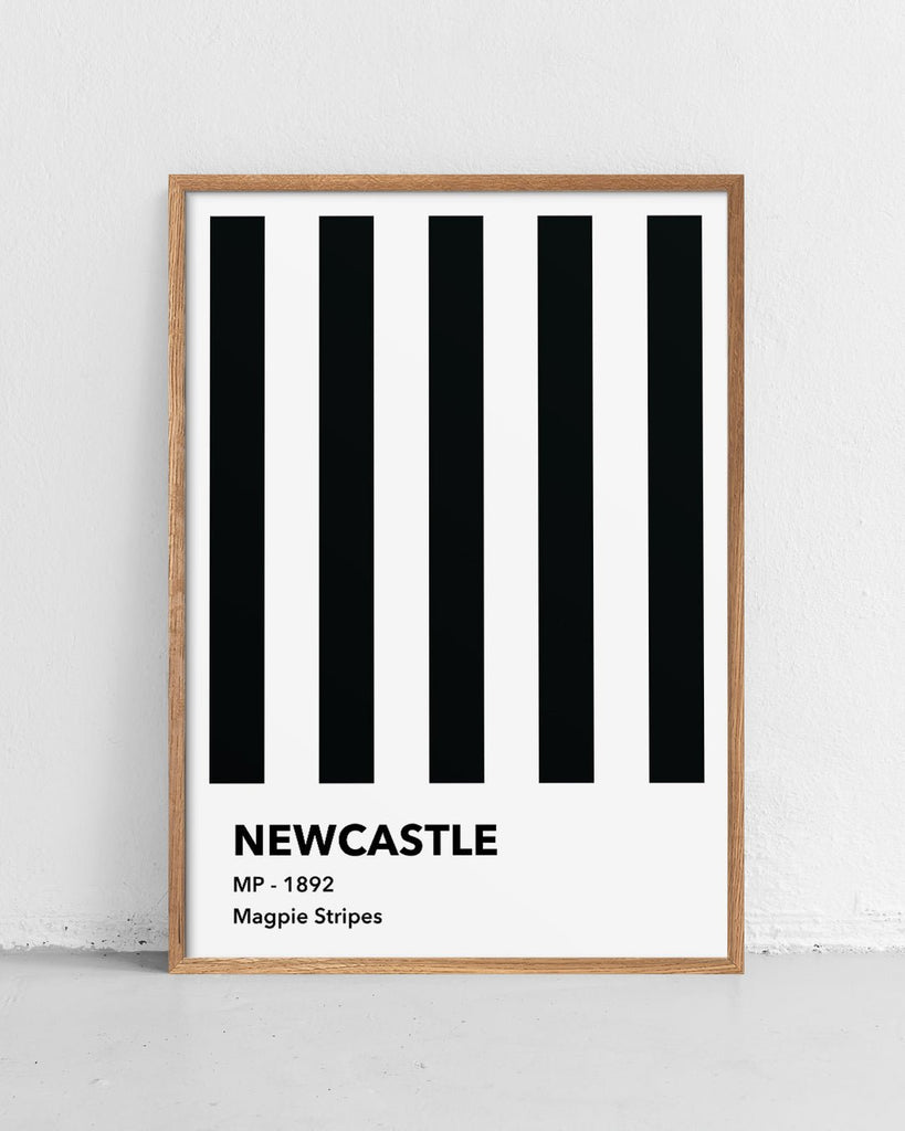 En Newcastle F.C. fodbold plakat med deres sorte og hvide striber fra Colors kollektionen stående på et gulv - Olé Olé